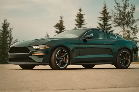A stylish 2019 Ford Mustang Bullitt parked on a scenic road, showcasing its sleek design and power.