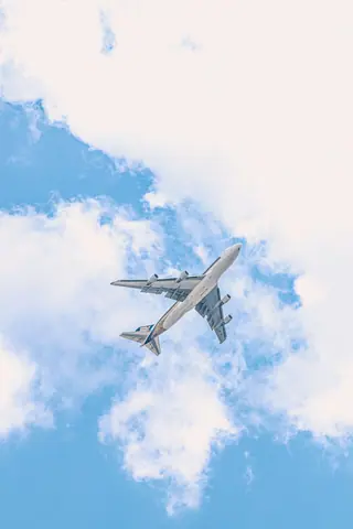 A passenger airplane soars through the blue sky amidst fluffy clouds, capturing the essence of flight.