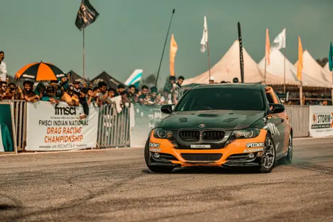 A thrilling black and orange race car speeding during a drag racing competition with spectators.