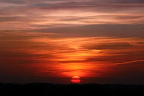 A breathtaking view of a vibrant sunset with dramatic clouds and vivid hues in the sky.