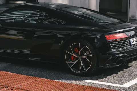 Close-up shot of a black luxury sports car with distinctive taillight and stylish wheels.