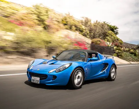 Blue sports car driving down a scenic highway with blurred motion, capturing a sense of speed.