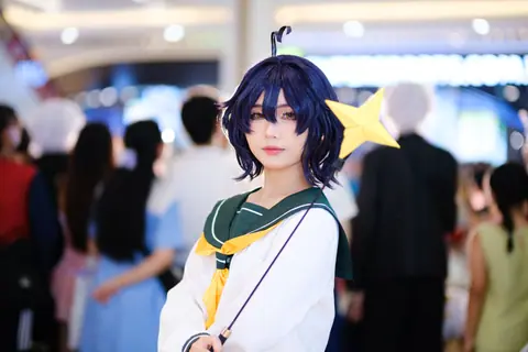 Cosplayer dressed as anime character with a star wand at a bustling indoor event.