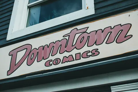 Close-up of a retro 'Downtown Comics' sign on a building facade.