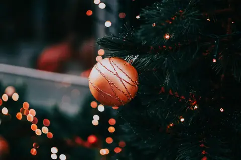 Close-up of a decorated Christmas tree with a bauble and twinkling lights.