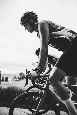 A black and white shot of a cyclist riding on a road, showcasing speed and determination.