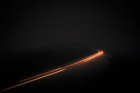 Long exposure photo capturing mesmerizing light streaks of moving cars on a dark road in San Francisco at night.