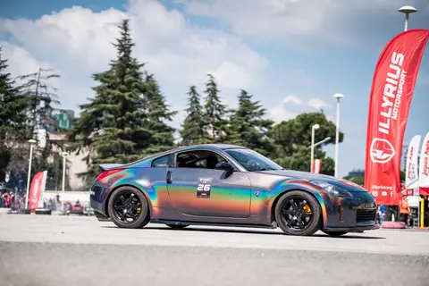 A vibrant Nissan with a holographic wrap showcased at an outdoor car event.