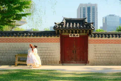 Scenic view of a traditional Korean gate with two women in hanbok in a peaceful outdoor setting.