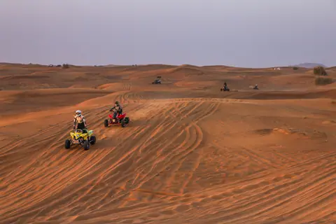 Exploring vast desert dunes on ATVs, perfect for an adrenaline-filled adventure.