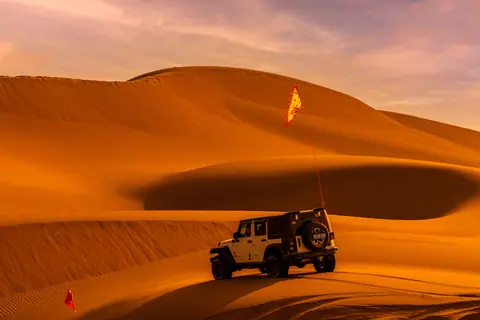 A thrilling SUV adventure in stunning desert sand dunes under the warm sunset light.