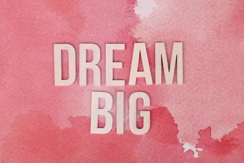 Motivational 'Dream Big' text on a pink watercolor background for encouragement.