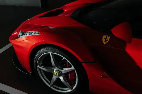 Close-up of a red sports car showcasing sleek design and aerodynamic curves under low lighting.