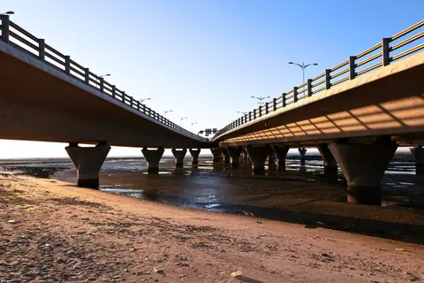 A stunning view of two parallel concrete bridges against a clear blue sky at sunset.