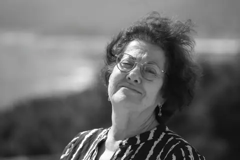 Sophisticated elderly woman smiling confidently outdoors. Black and white portrait.