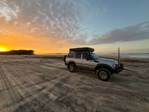 Explore off-road adventure in a 4WD at stunning Rainbow Beach during a breathtaking sunrise.