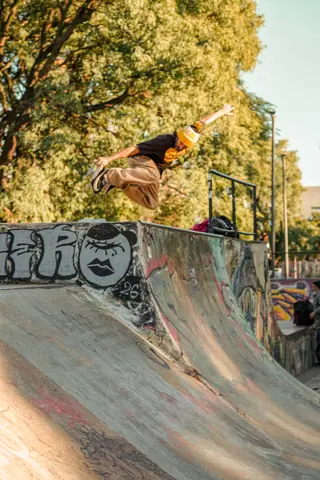 A skateboarder in mid-air performing a trick at a bustling Buenos Aires skate park, capturing urban skate culture.