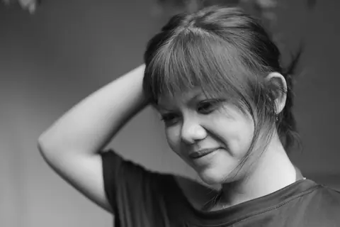 A thoughtful black and white portrait capturing a woman smiling with a reflective pose.