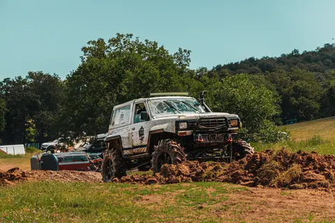 White off-road vehicle navigates rugged terrain under clear sky, showcasing adventurous spirit.