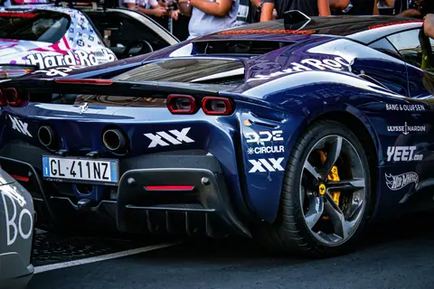 A sleek, high-end sports car showcased at an outdoor automotive event, attracting a crowd.