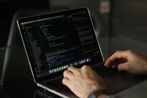 Close-up of hands coding on a laptop, focusing on programming productivity.