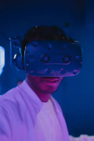 Close-up of a man enjoying a VR experience under pink and blue lights wearing a virtual reality headset.
