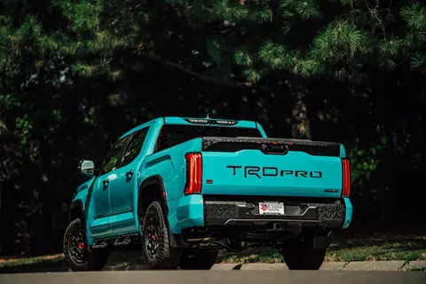 Teal pickup truck showcasing TRD Pro model parked outdoors with pine trees.