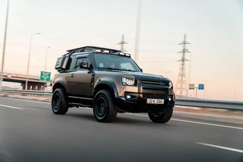 A Land Rover Defender speeds on a highway in Erbil, Iraq during the day.
