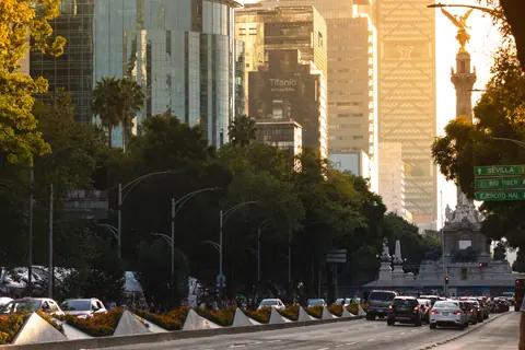 Urban scene of Ciudad de México with iconic Angel of Independence and skyscrapers at sunset.