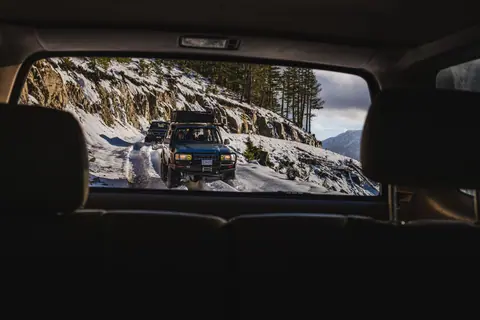 Rugged 4x4 vehicles navigate snowy mountain paths, perfect for adventure travel enthusiasts.