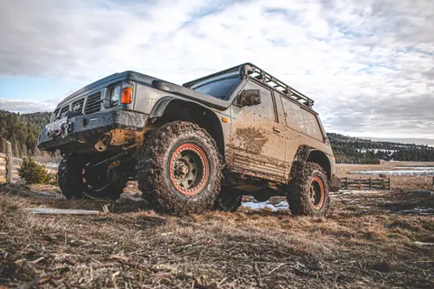 A muddy off-road vehicle on a rugged terrain with a cloudy sky backdrop, ideal for adventure themes.