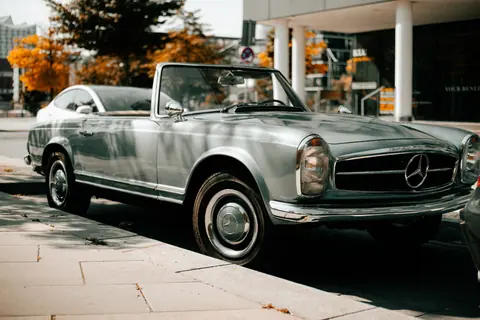 Elegant classic Mercedes-Benz parked on city street in autumn setting.