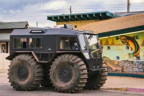 A rugged exploration vehicle with oversized tires parked in Williams, Arizona on a scenic day.