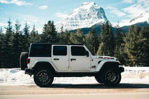 White Jeep Wrangler parked in snowy Jasper National Park, Alberta.