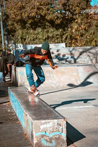 A skillful skateboarder performing tricks on a ledge in a sunny Buenos Aires skatepark.