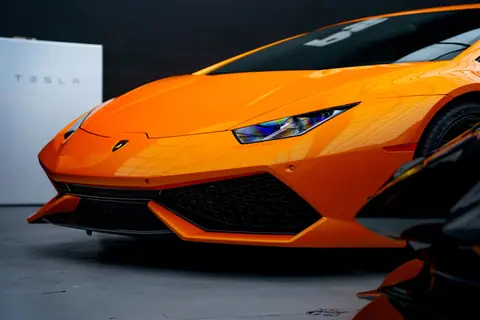 Close-up of a vibrant orange sports car indoors. Sleek and powerful design captured beautifully.