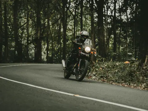 Motorcyclist riding through a forested road, showcasing speed and adventure.