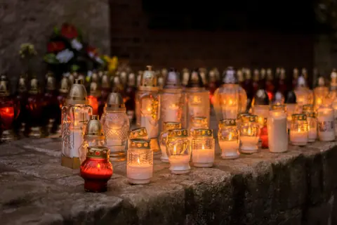 A serene scene of votive candles glowing softly in a cemetery during All Saints' Day.