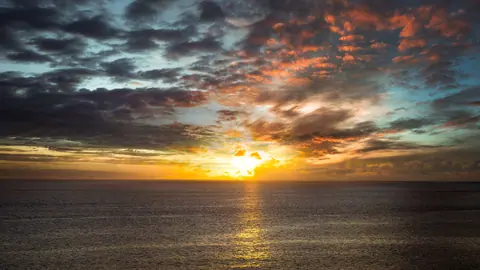 A breathtaking sunset over the ocean with dramatic clouds and vivid colors.
