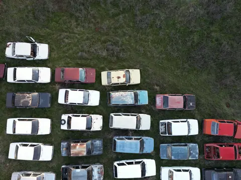 Drone shot of rusting abandoned cars lined up in a field in Denizli, Turkey.