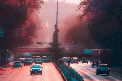 Evening traffic on Paseo de la Reforma in Mexico City with vibrant lighting and the Mexican flag in view.