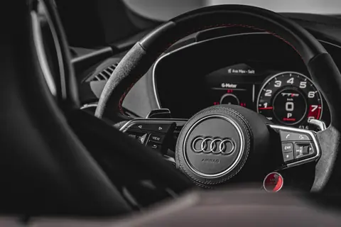 Close-up of a luxury car's interior showing steering wheel and dashboard details.