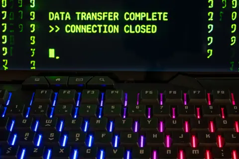 Close-up of a RGB lit keyboard with a screen displaying 'Data Transfer Complete'.