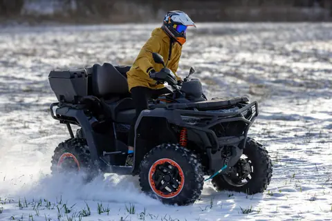 Person riding an ATV in a snowy field, showcasing winter outdoor adventure and off-road fun.