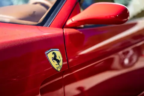 Detailed view of a red sports car, focusing on the logo and side mirror.