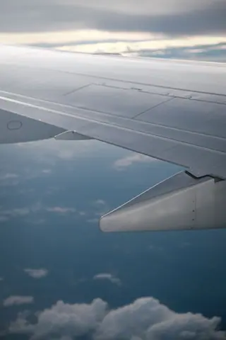 Serene aerial view of airplane wing flying above fluffy clouds in daylight.