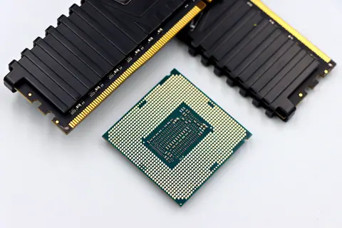 A CPU and RAM sticks displayed on a white surface, showcasing computer hardware components.
