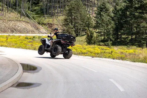 Man riding ATV on scenic mountain road with lush greenery in Zlatibor, Serbia.