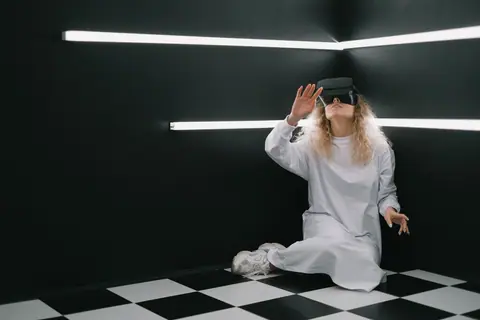 A woman in a white dress explores virtual reality in a modern, dark room.