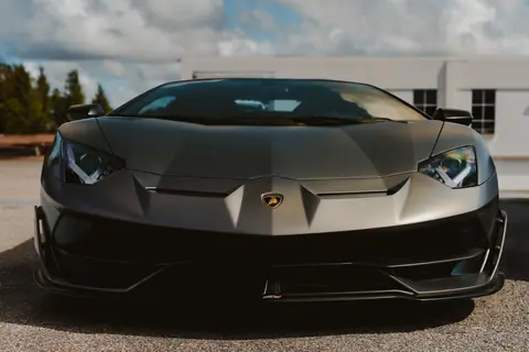 Front view of a stylish black luxury sports car parked outdoors under a clear sky.